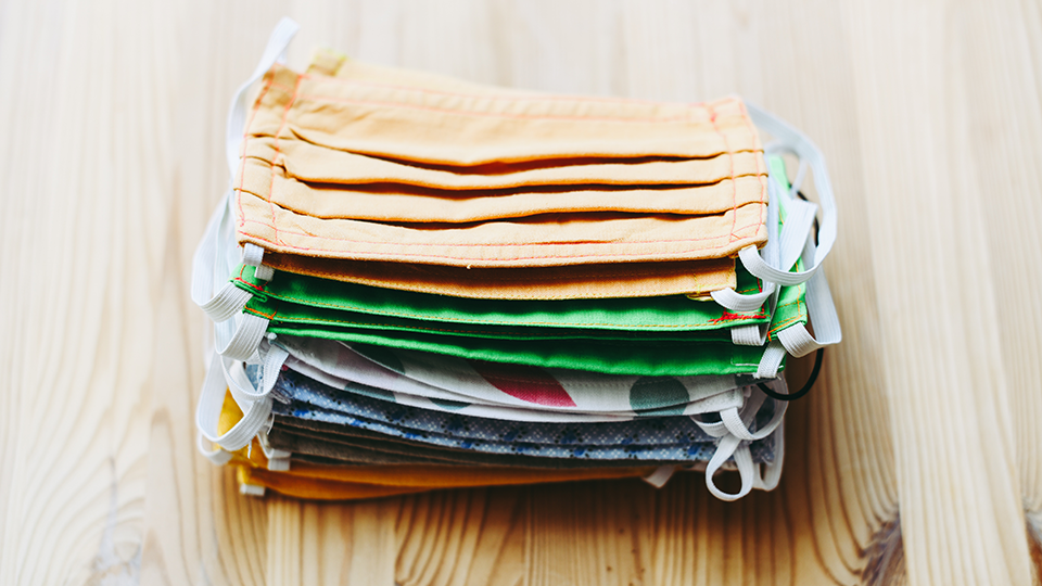 Small pile of multi-coloured, reusable face masks.