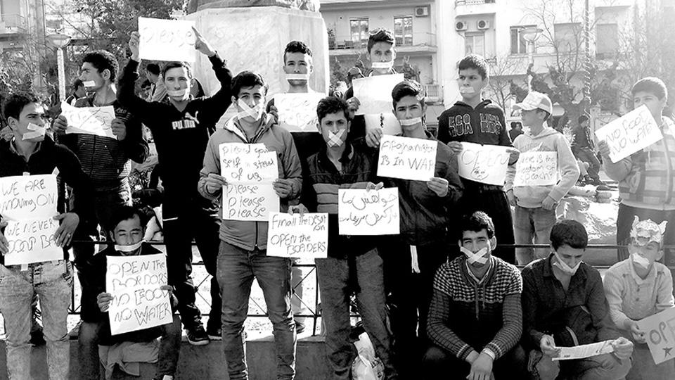 A black and white photo of men standing with protest signs and taped mouths