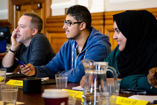 Three students sit at a desk taking part in a Law mock jury exercise